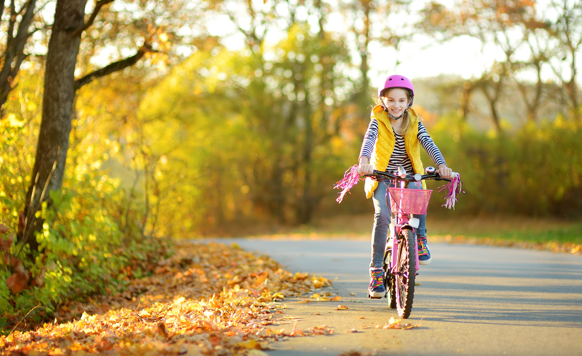 Ett barn sitter i en barnstol på en pakethållare på en cykel. Barnet ler. Ryggtavla syns på en pappa som kör cykeln. 
