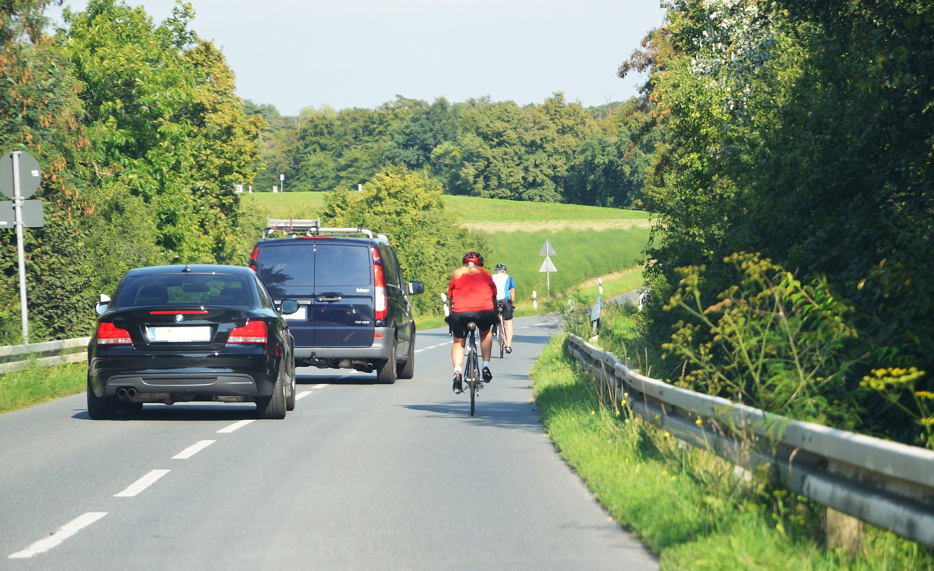Bilar kör om cyklister på landsväg.