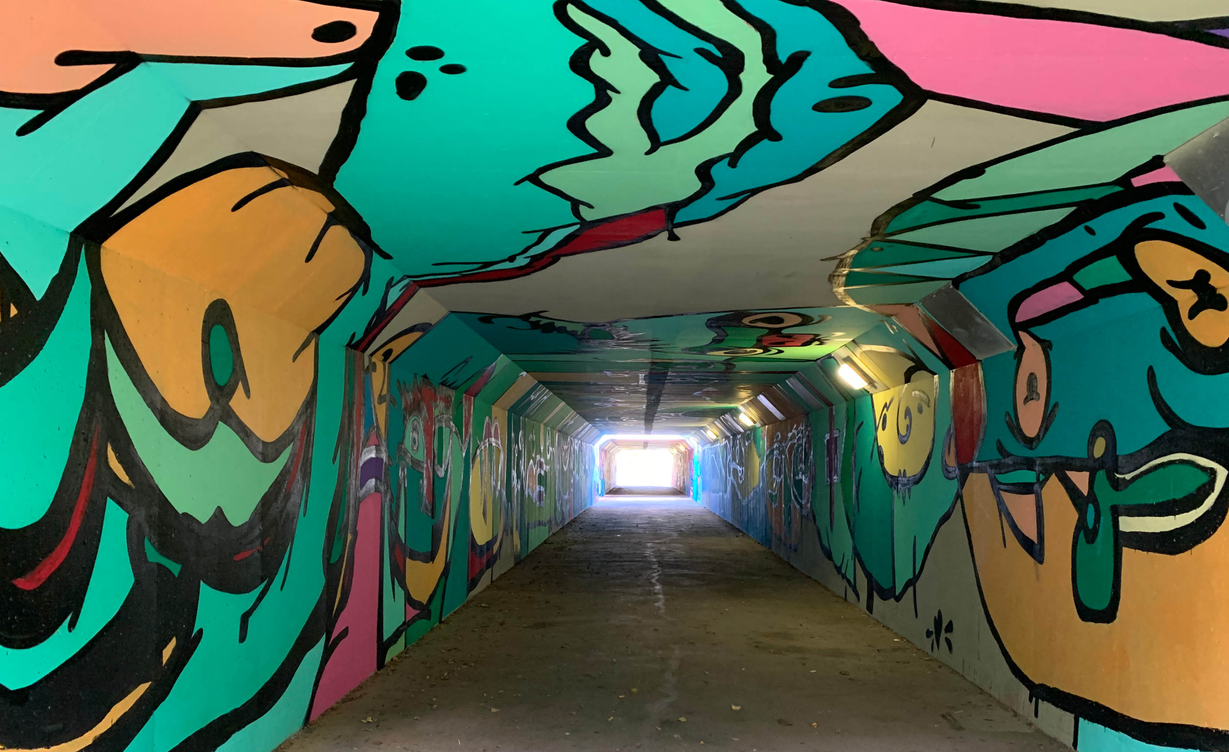Färgglatt målad tunnel med olika former och figurer.